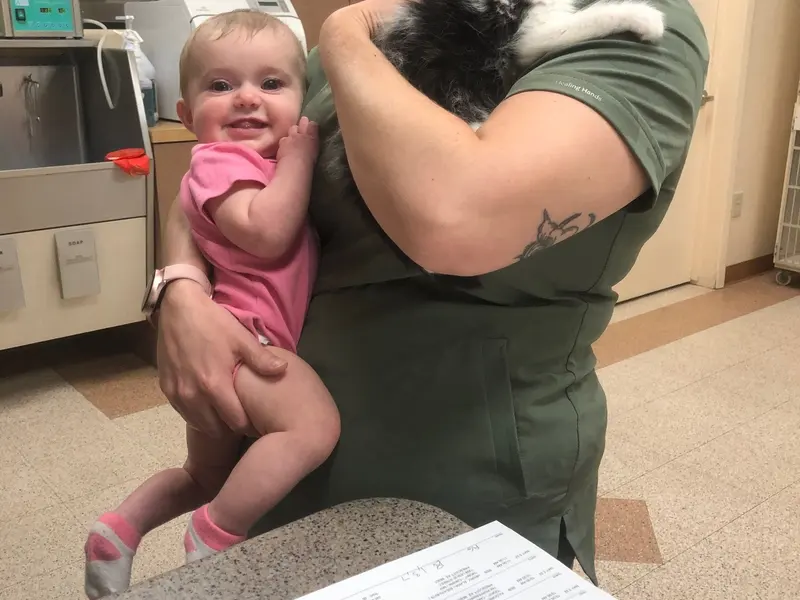 A technician holding a clinic cat alongside a young visitor.