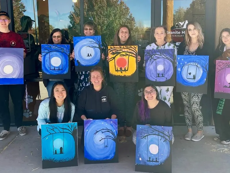 The team showing off their paintings at a paint night.