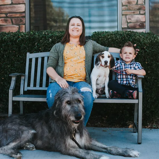 Dr. Katherine Siens on the bench in front of the practice with her family and dogs, including a tall Irish wolfhound.