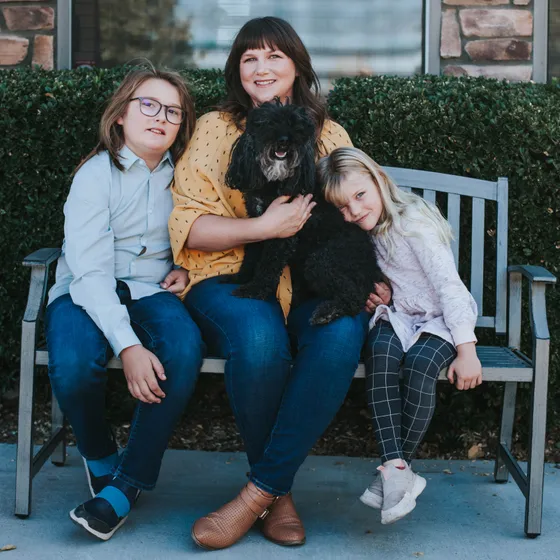 Dr. Sarah Bason on the bench in front of the practice with her two children and one of the family dogs.